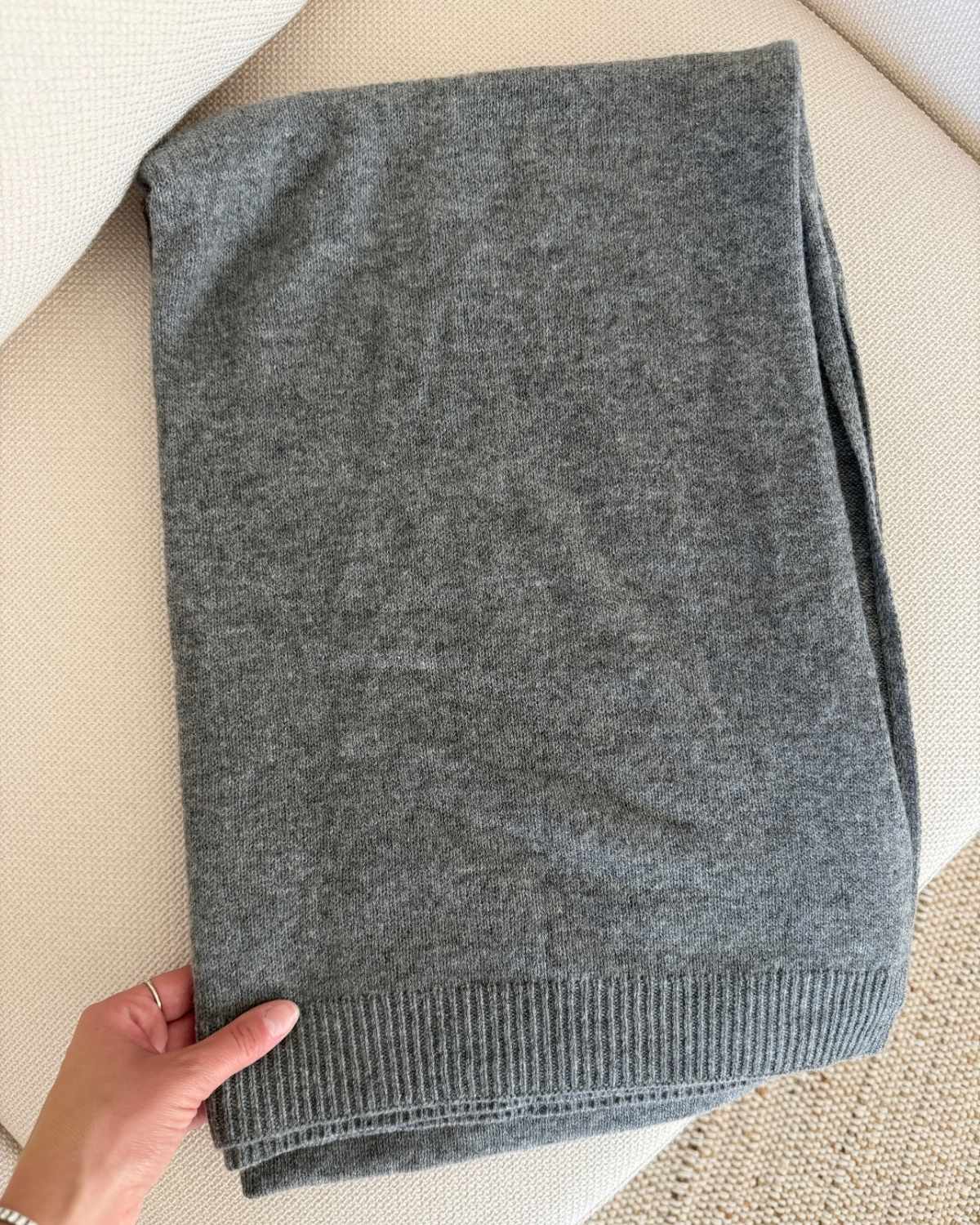 Gray wool and cashmere scarf wrap folded on a cream chair